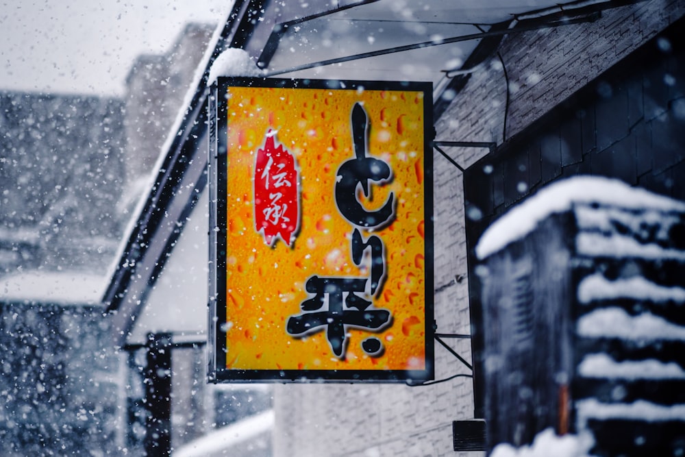 a sign hanging from the side of a building covered in snow