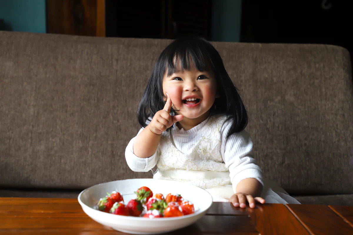 いちごの入ったボウルを前に笑顔の子ども