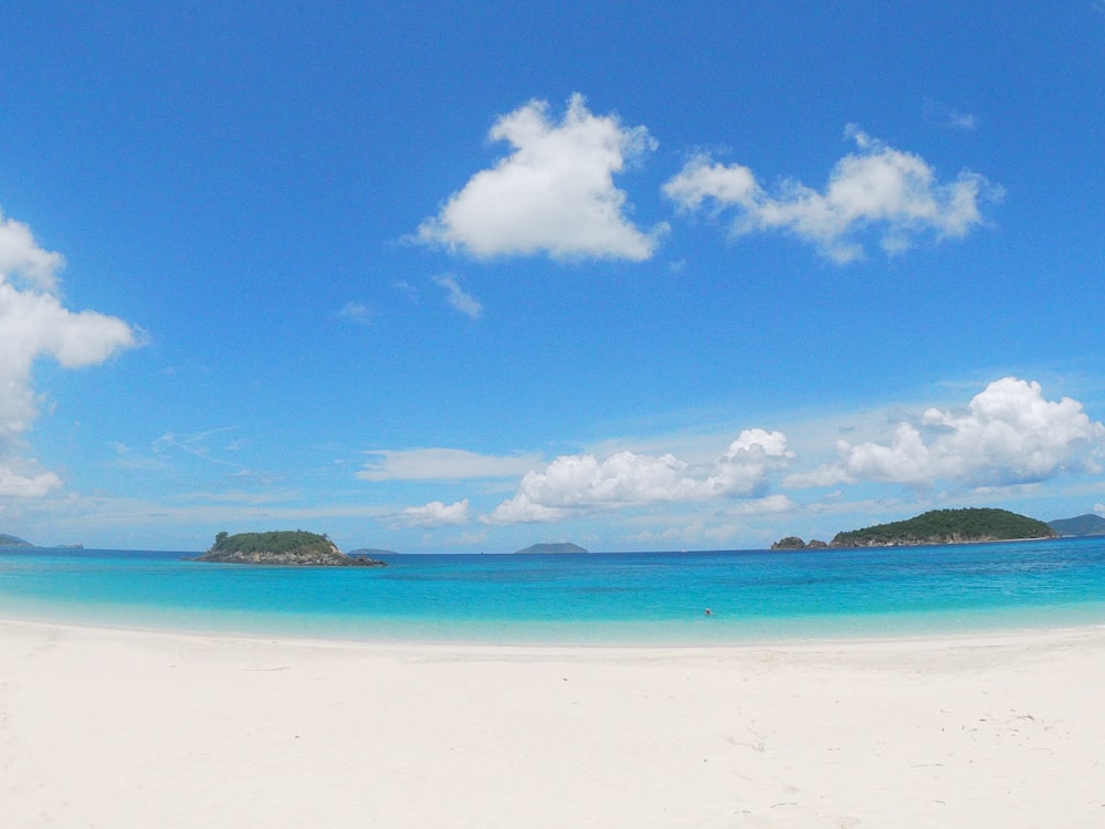 a sandy beach with blue water and white sand