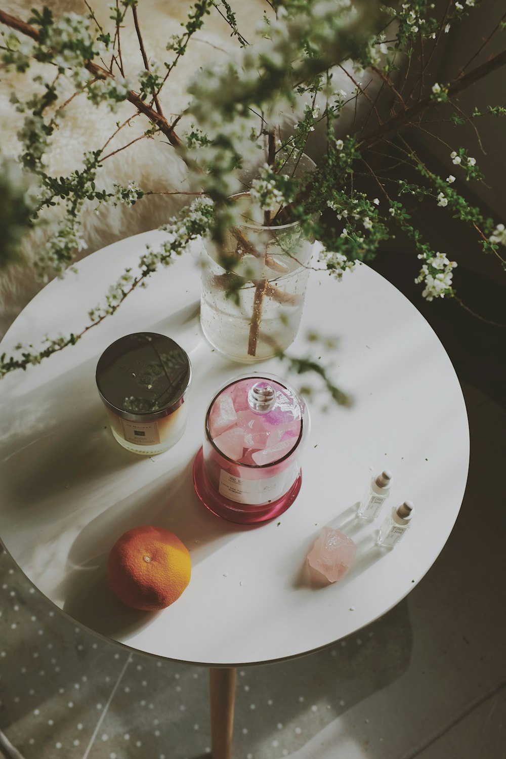 une table avec un vase de fleurs et une bougie dessus