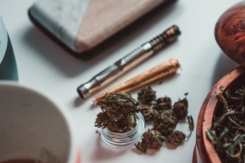 a wooden bowl filled with marijuana next to a cup of coffee