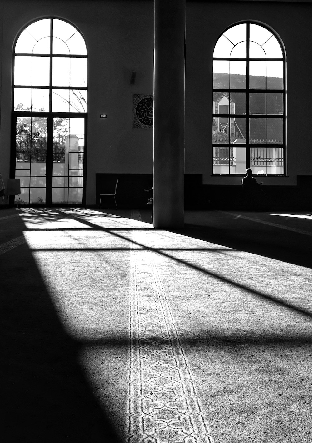 a large room with two large windows and a rug on the floor