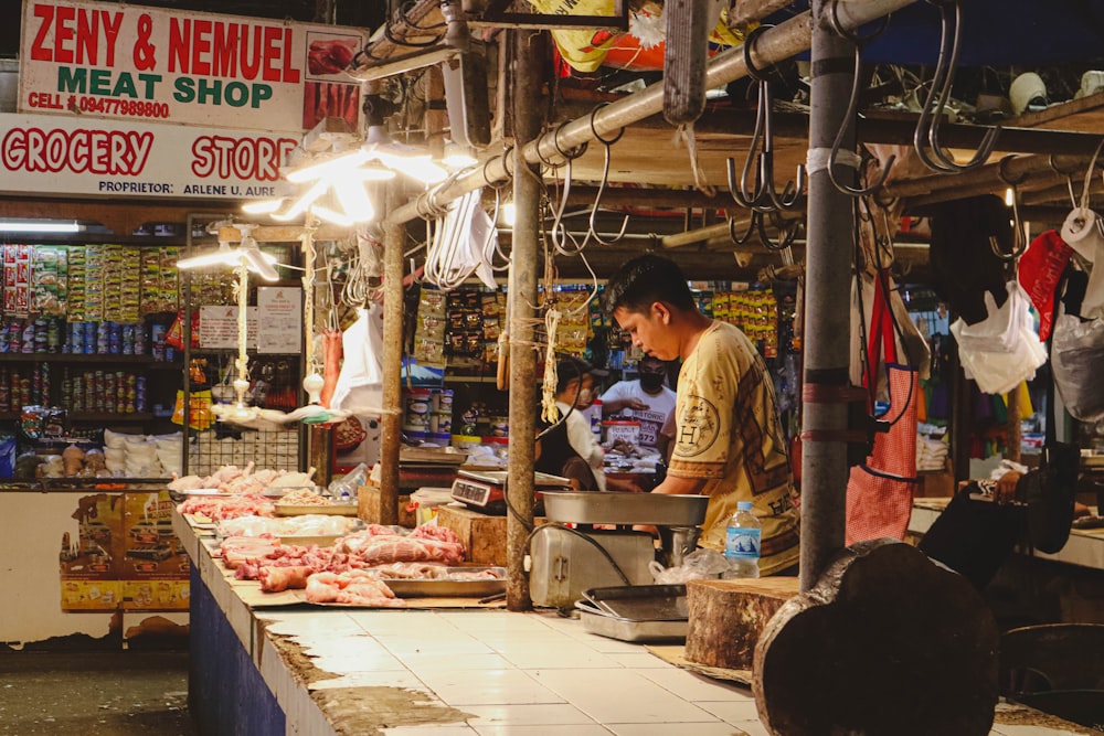 a man standing in front of a store filled with meat