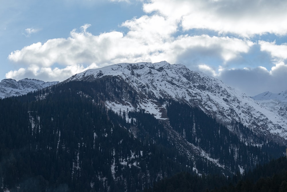 a mountain covered in snow under a cloudy sky