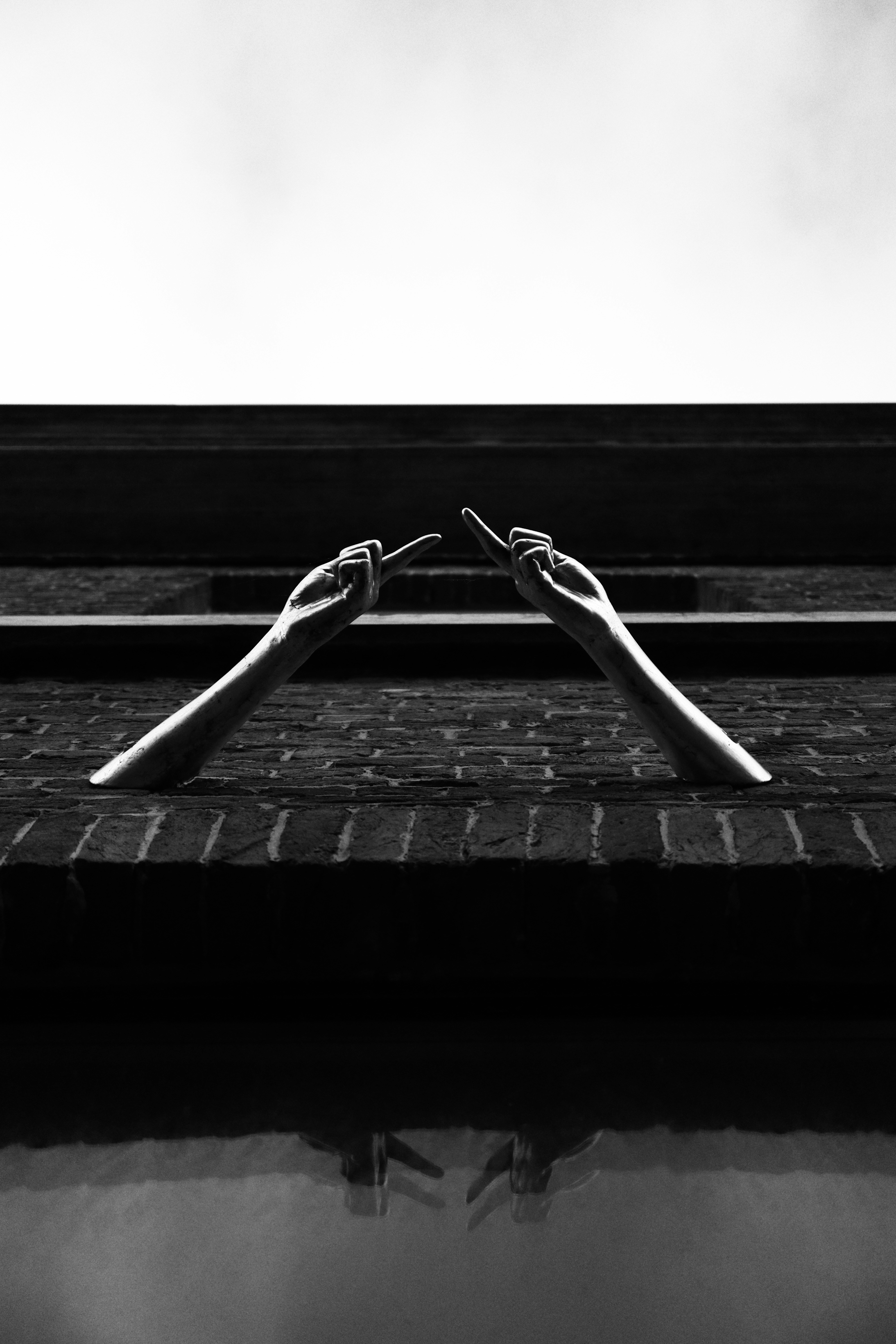 a black and white photo of two hands reaching out of a window