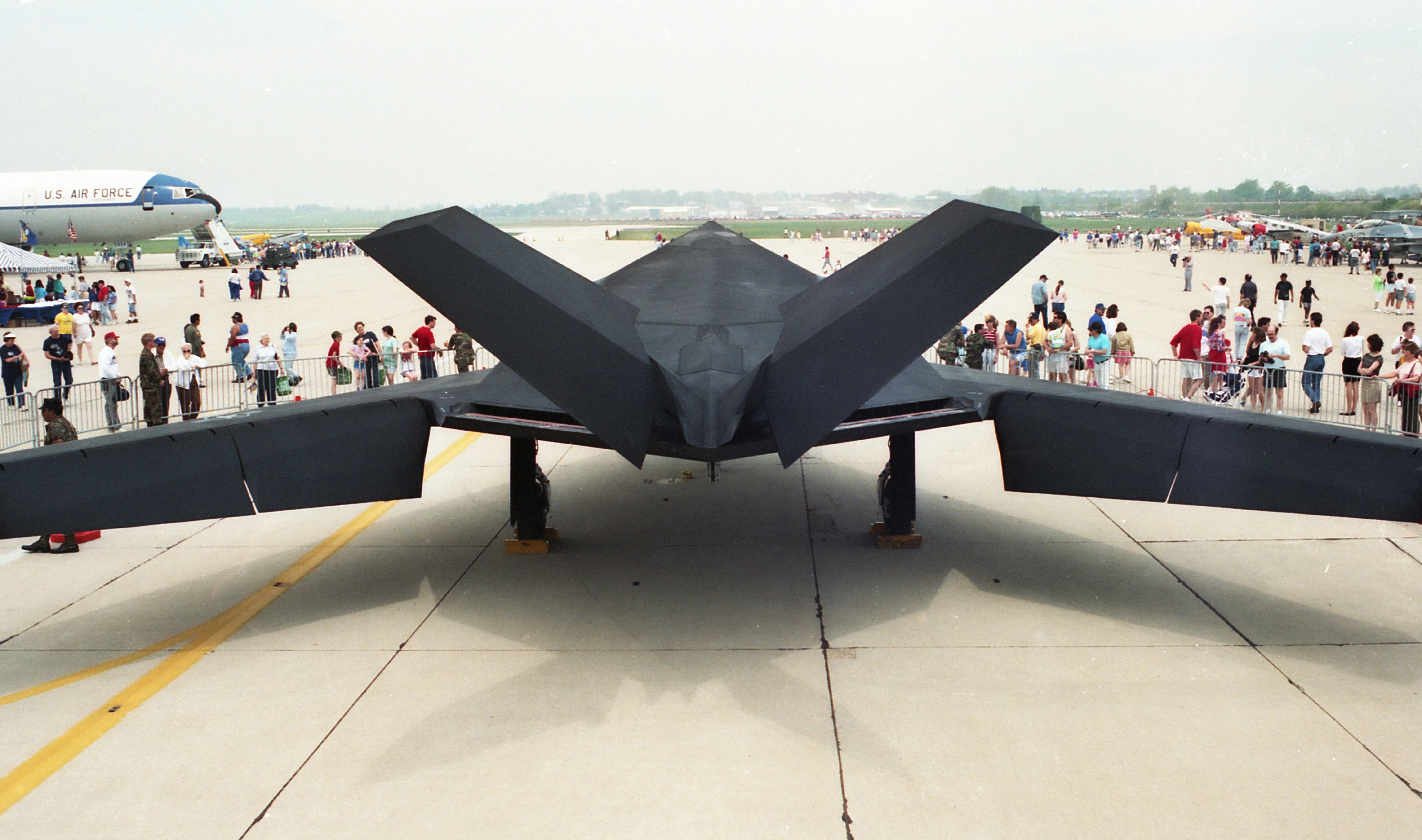 a large jetliner sitting on top of an airport tarmac, F-117 Nighthawk at an airshow.   Photo was made from scanned 35mm film.