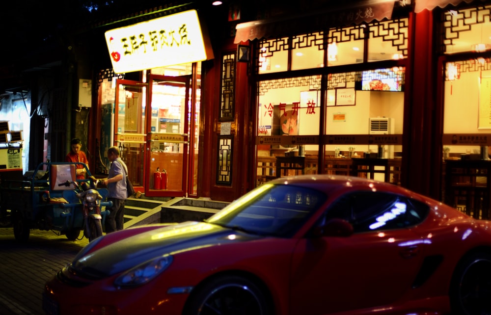 Un coche deportivo rojo estacionado frente a un restaurante