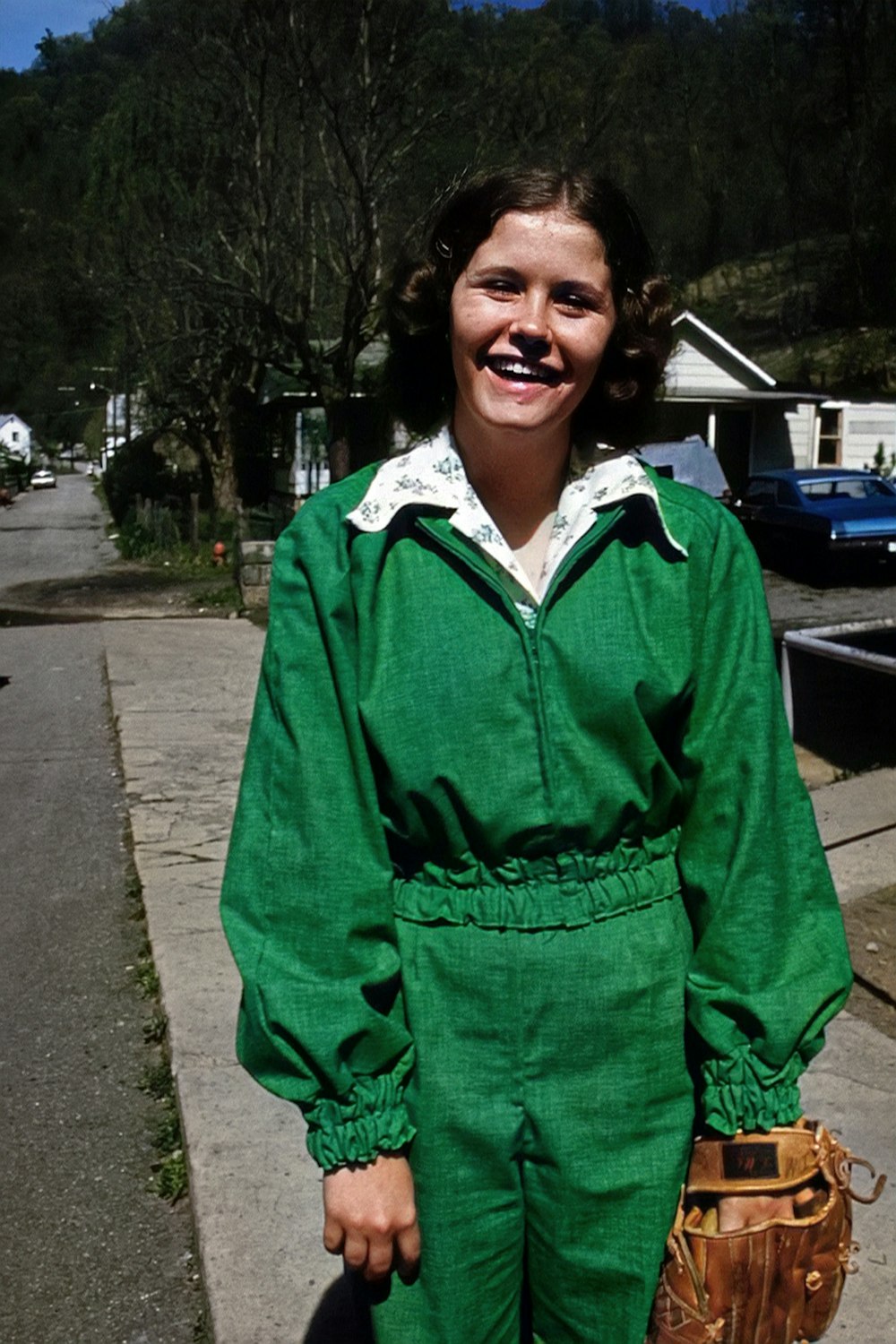 a woman in a green jumpsuit holding a baseball glove