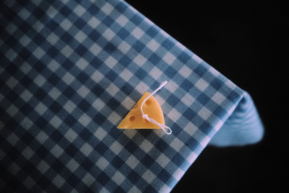 a piece of cheese sitting on top of a blue and white checkered shirt
