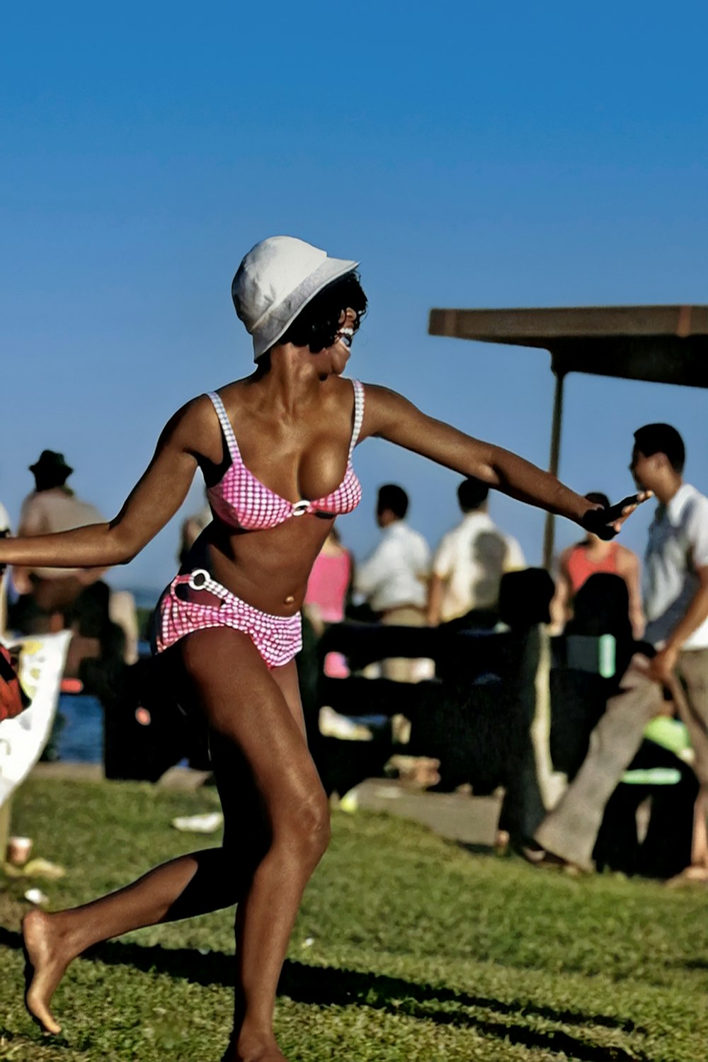 a woman in a bikini and hat playing frisbee
