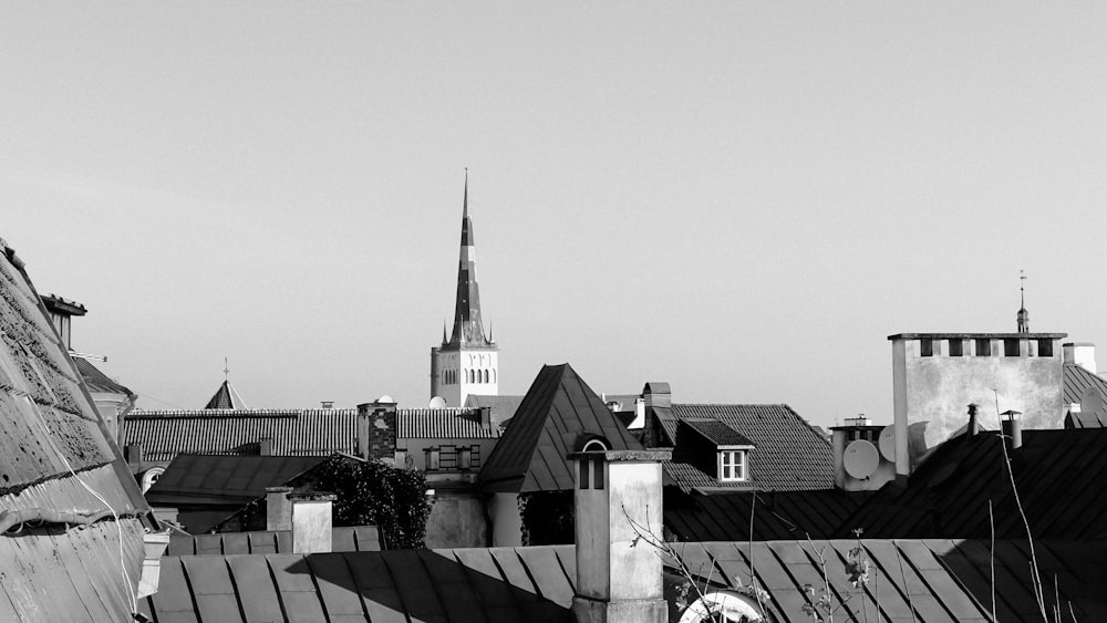 uma foto em preto e branco de telhados com uma torre do relógio ao fundo