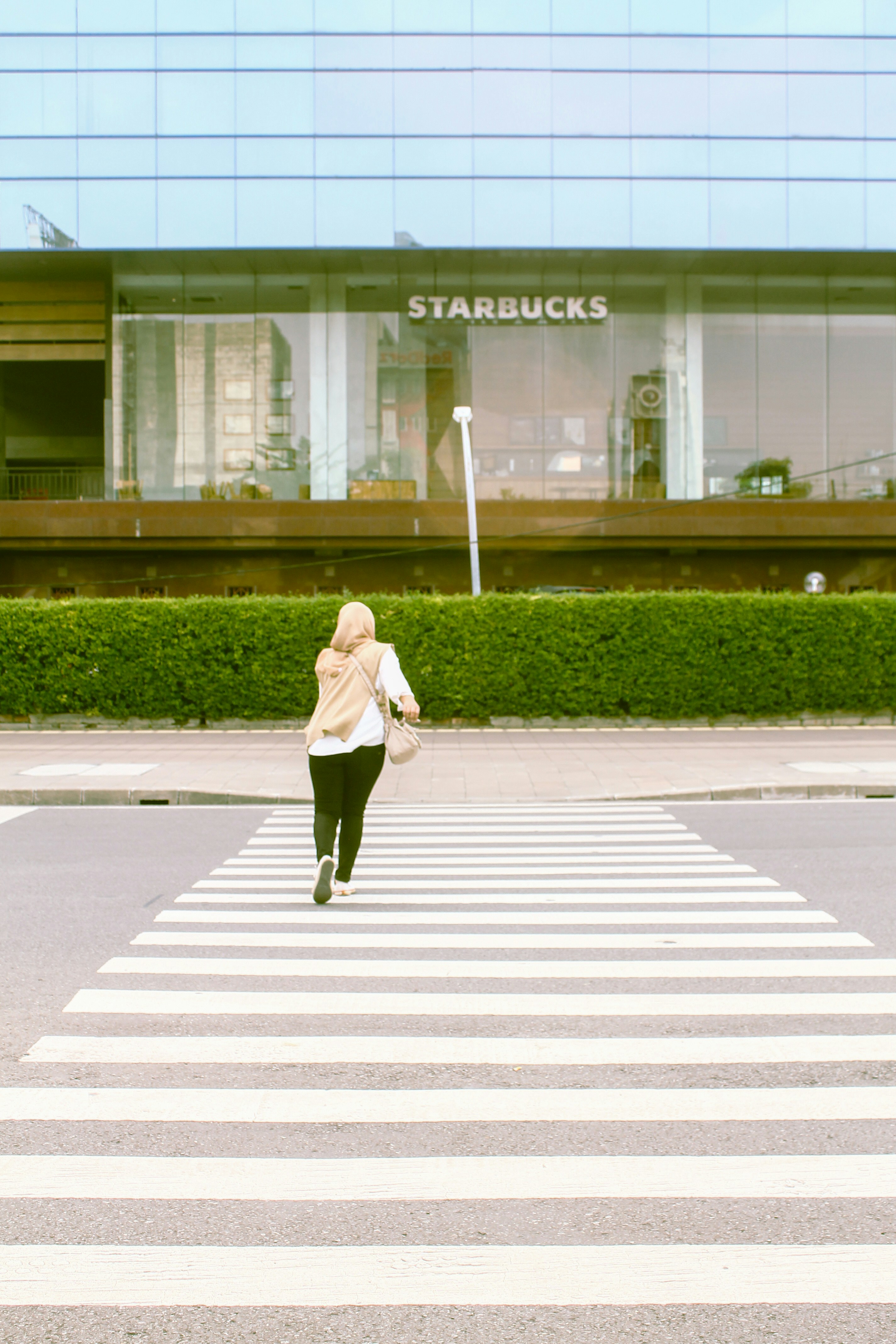 a woman walking across a cross walk in front of a building