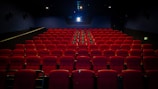 an empty theater with red seats and a projector screen