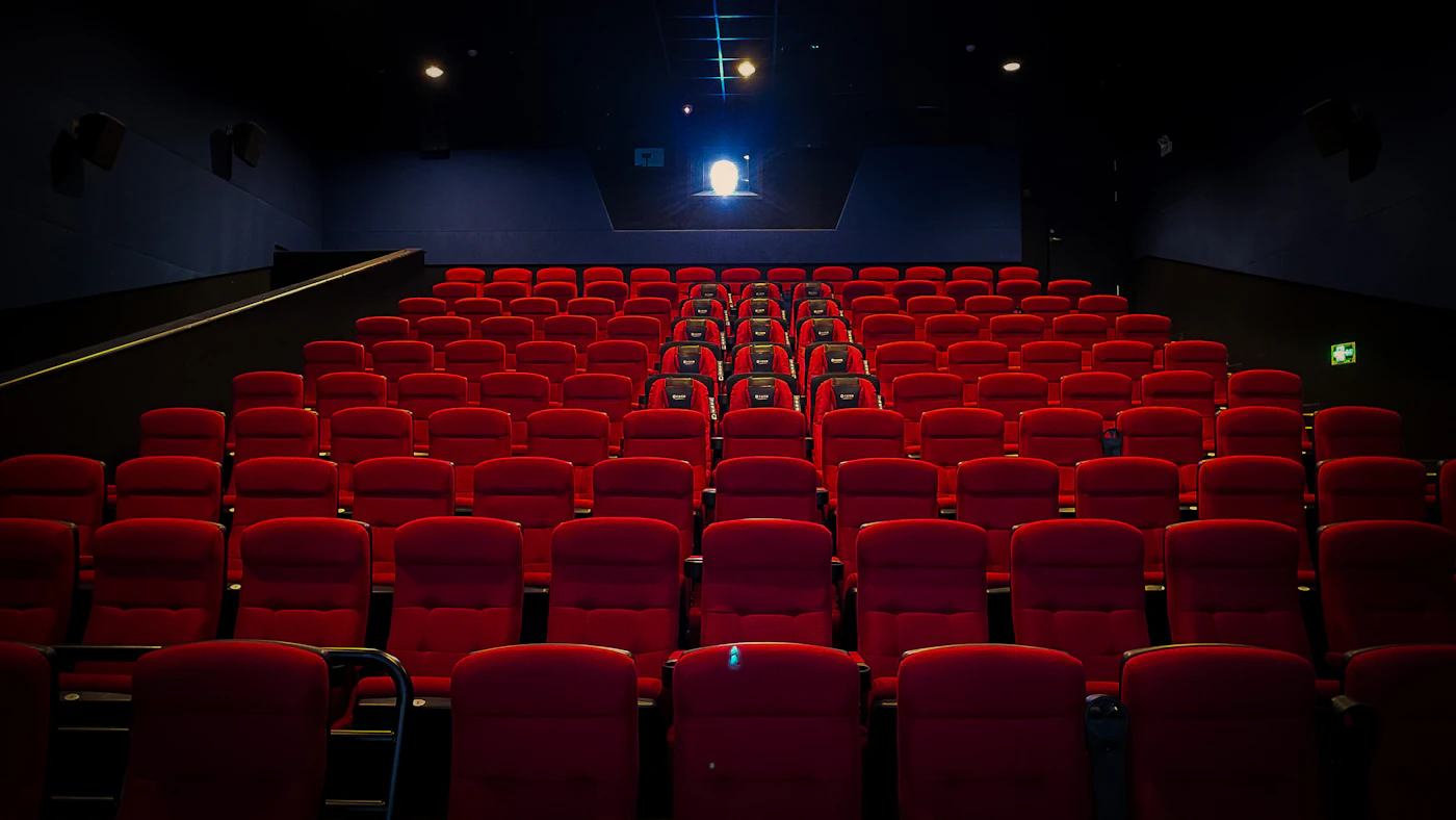 Empty cinema with red seats facing a screen