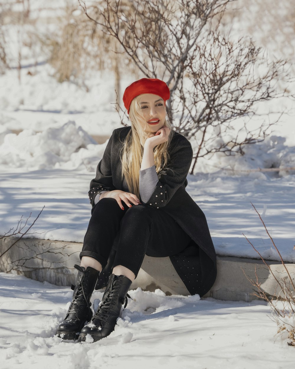a woman sitting in the snow wearing a red hat