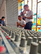 A diverse group of musicians sharing ideas around a mixing console.