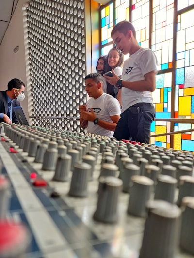 A group of sound engineers collaborating around mixing consoles during a workshop.
