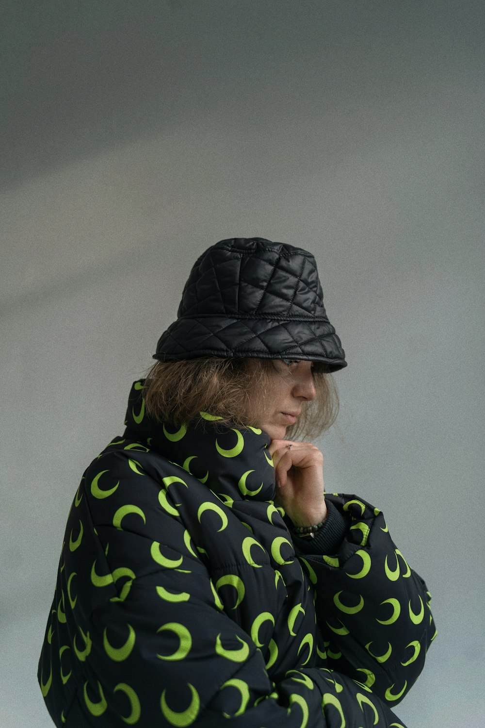 a person wearing a black hat and a green and black jacket