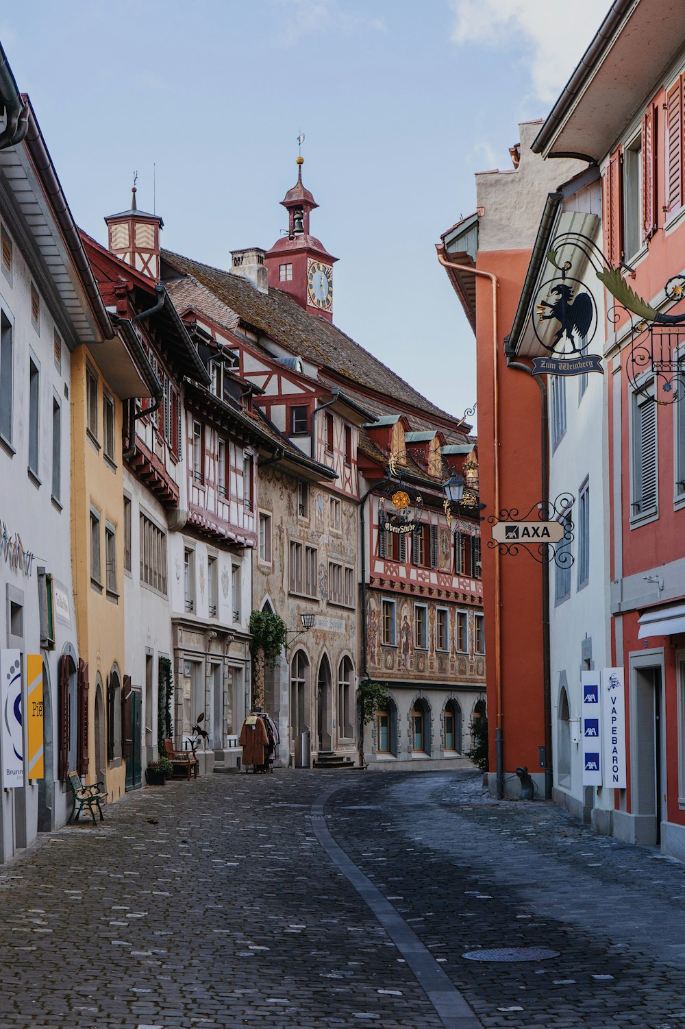 a cobblestone street lined with buildings and a clock tower