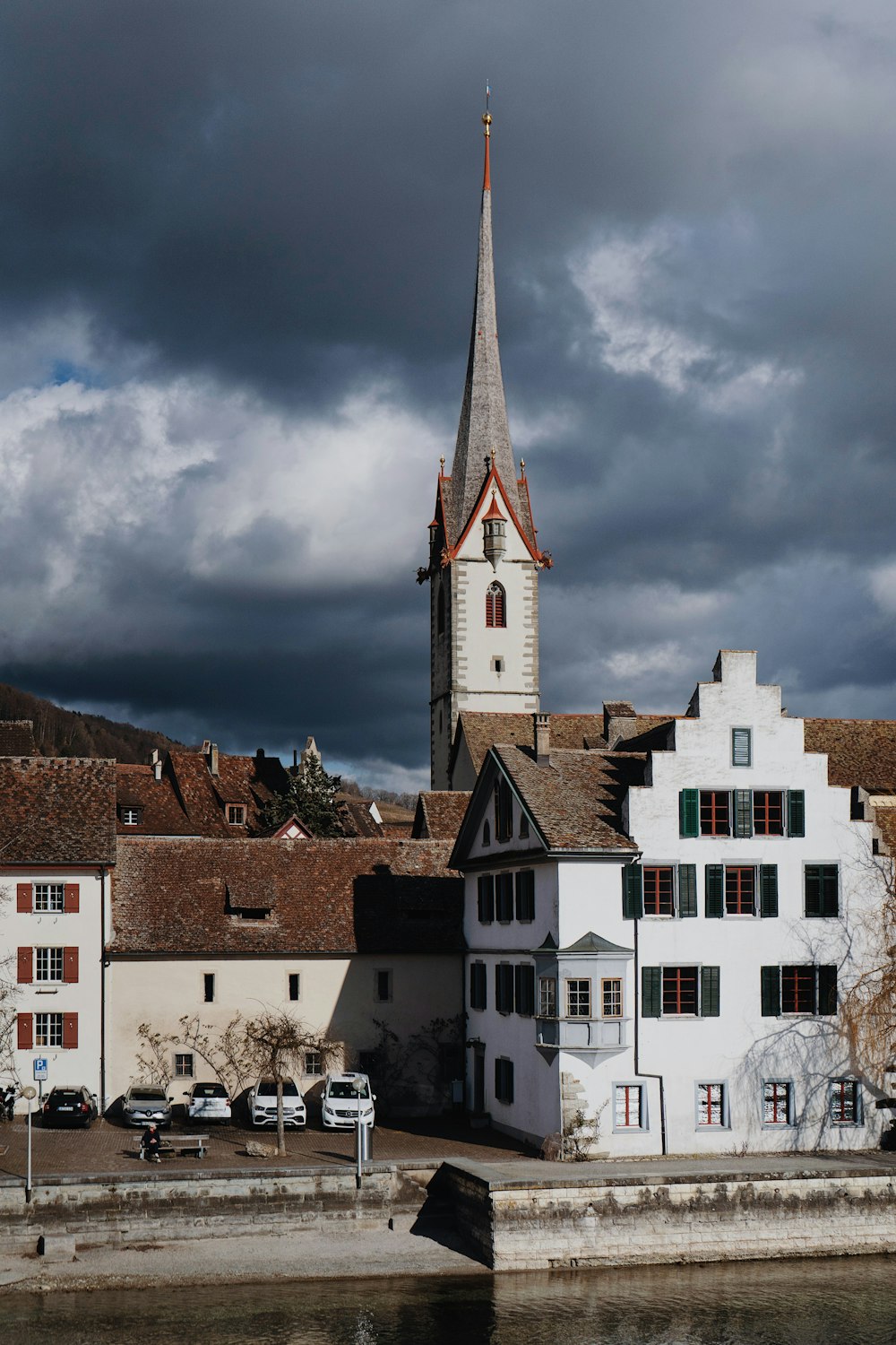 a white building with a steeple next to a body of water