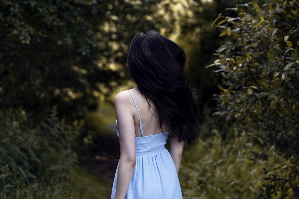 a woman in a blue dress walking down a path