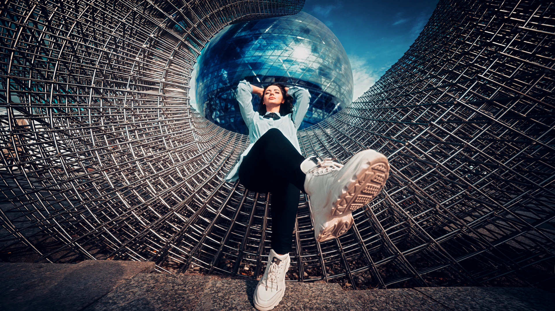 a woman in a white shirt and black pants standing in a metal structure