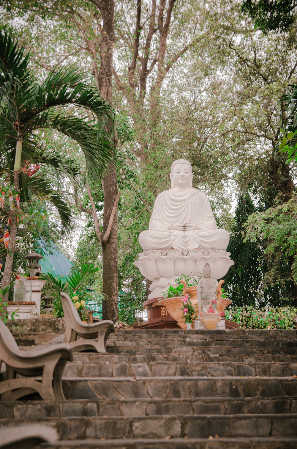 a large white buddha statue sitting in the middle of a park