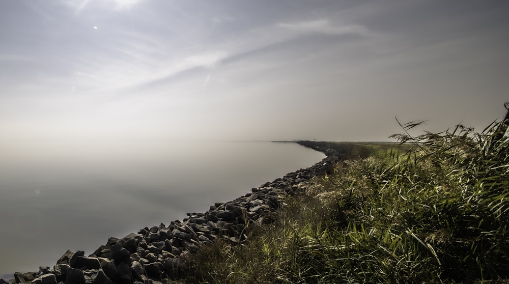 a large body of water sitting next to a lush green field