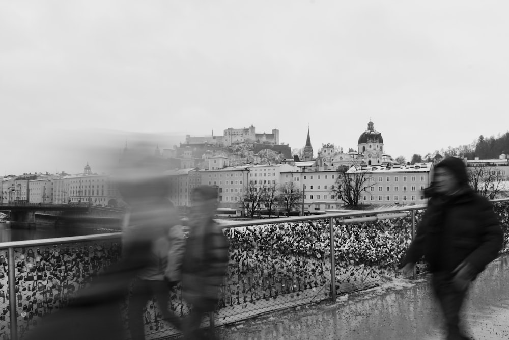 a black and white photo of people walking on a bridge