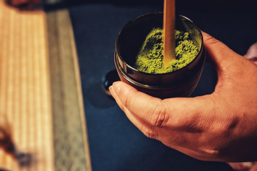 a person holding a cup with a green substance in it