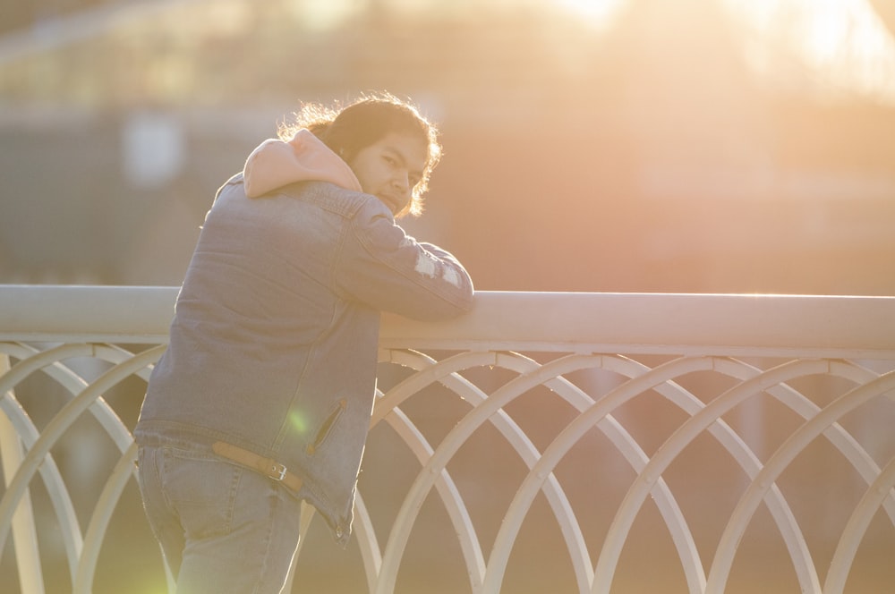 a man leaning against a fence with his head on his hands