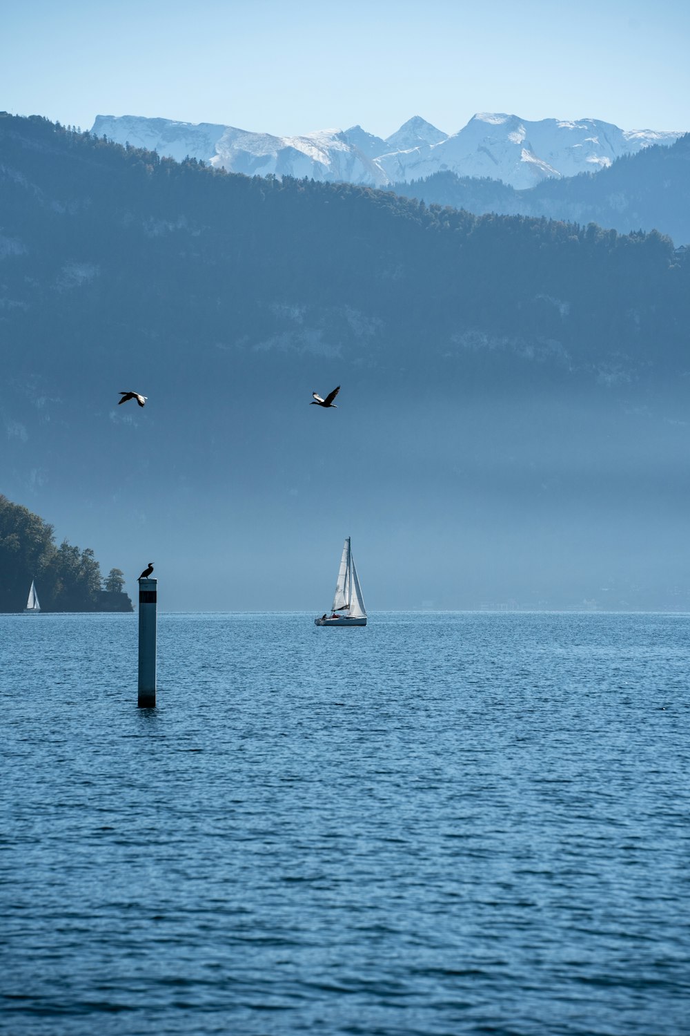 a sailboat in the water with mountains in the background