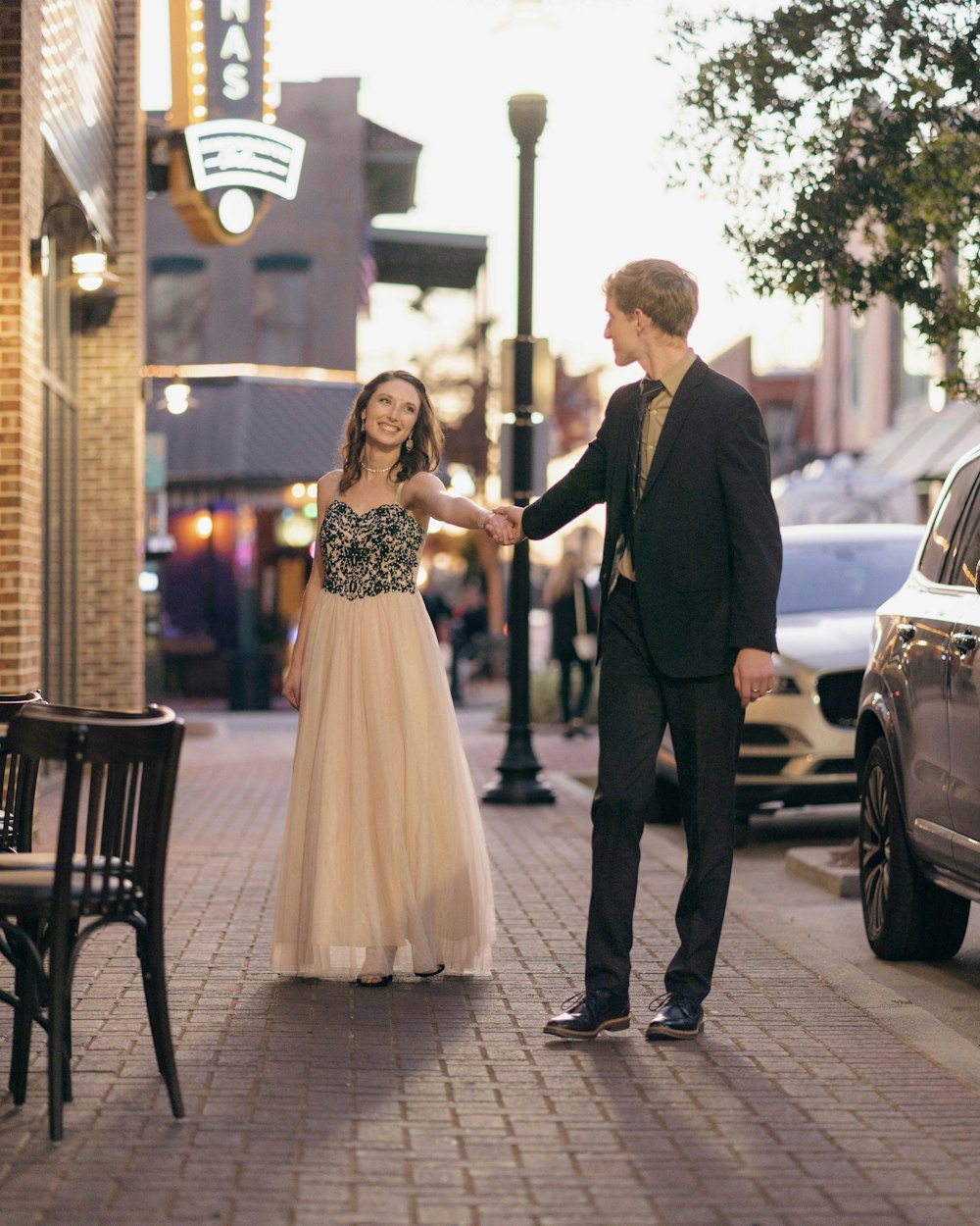 a man and a woman holding hands on a sidewalk