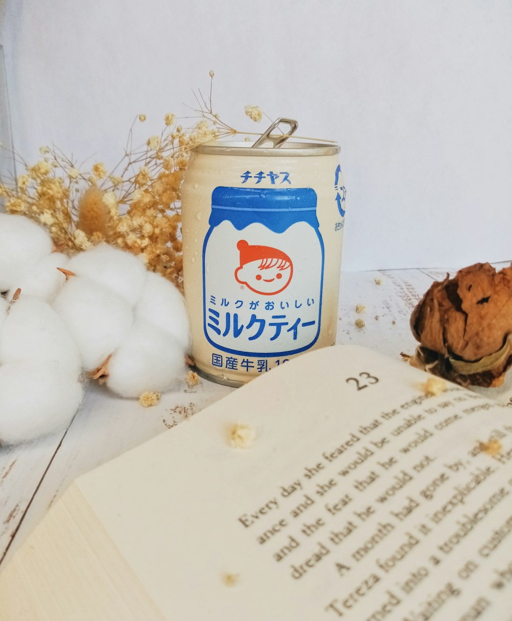 a book, a can of milk and cotton floss on a table