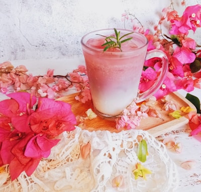 A close-up of a sparkling snow globe drink flask filled with vibrant pink liquid, resting on a rose gold tray.