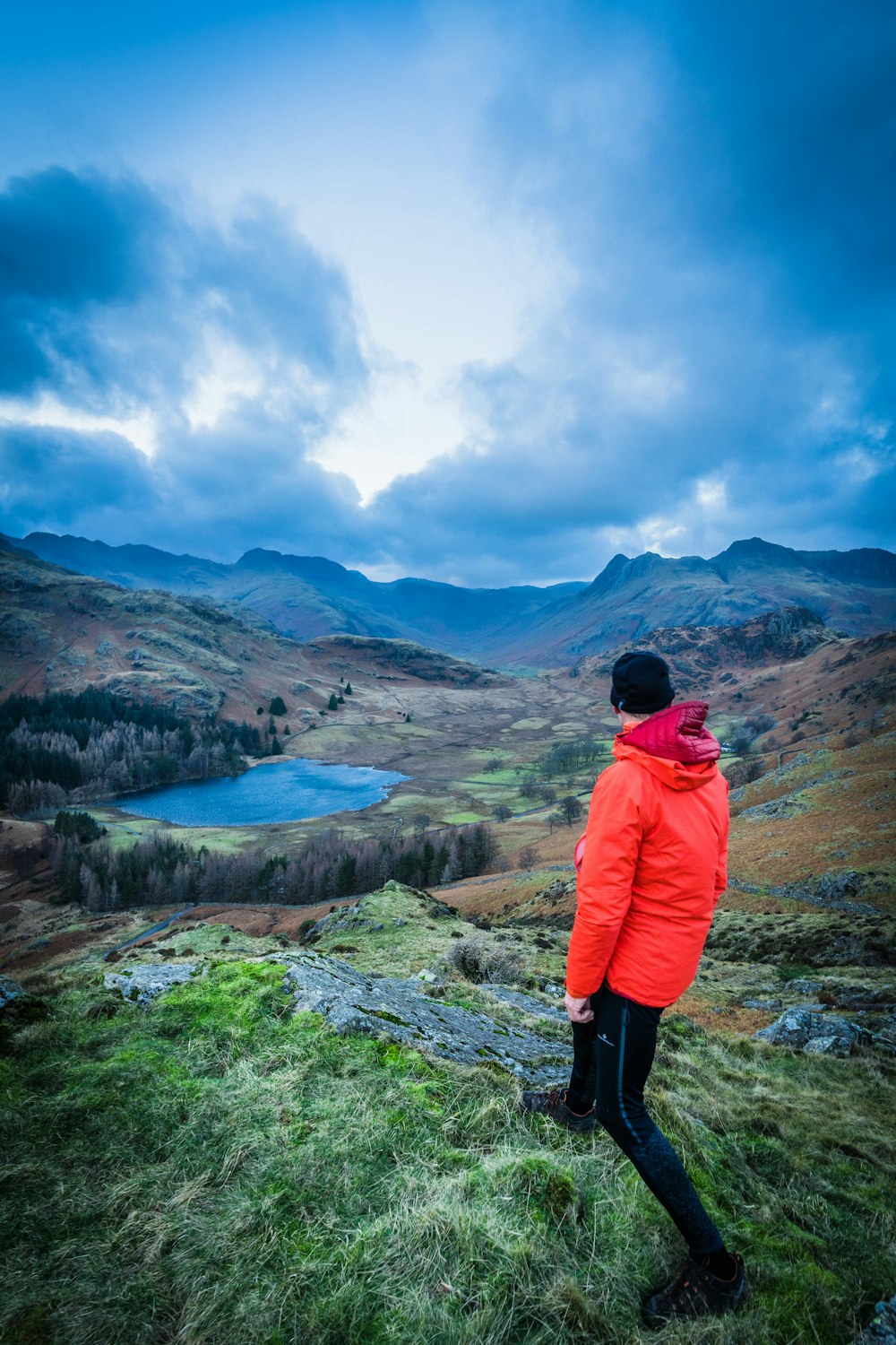 uma pessoa de pé em uma colina olhando para um lago