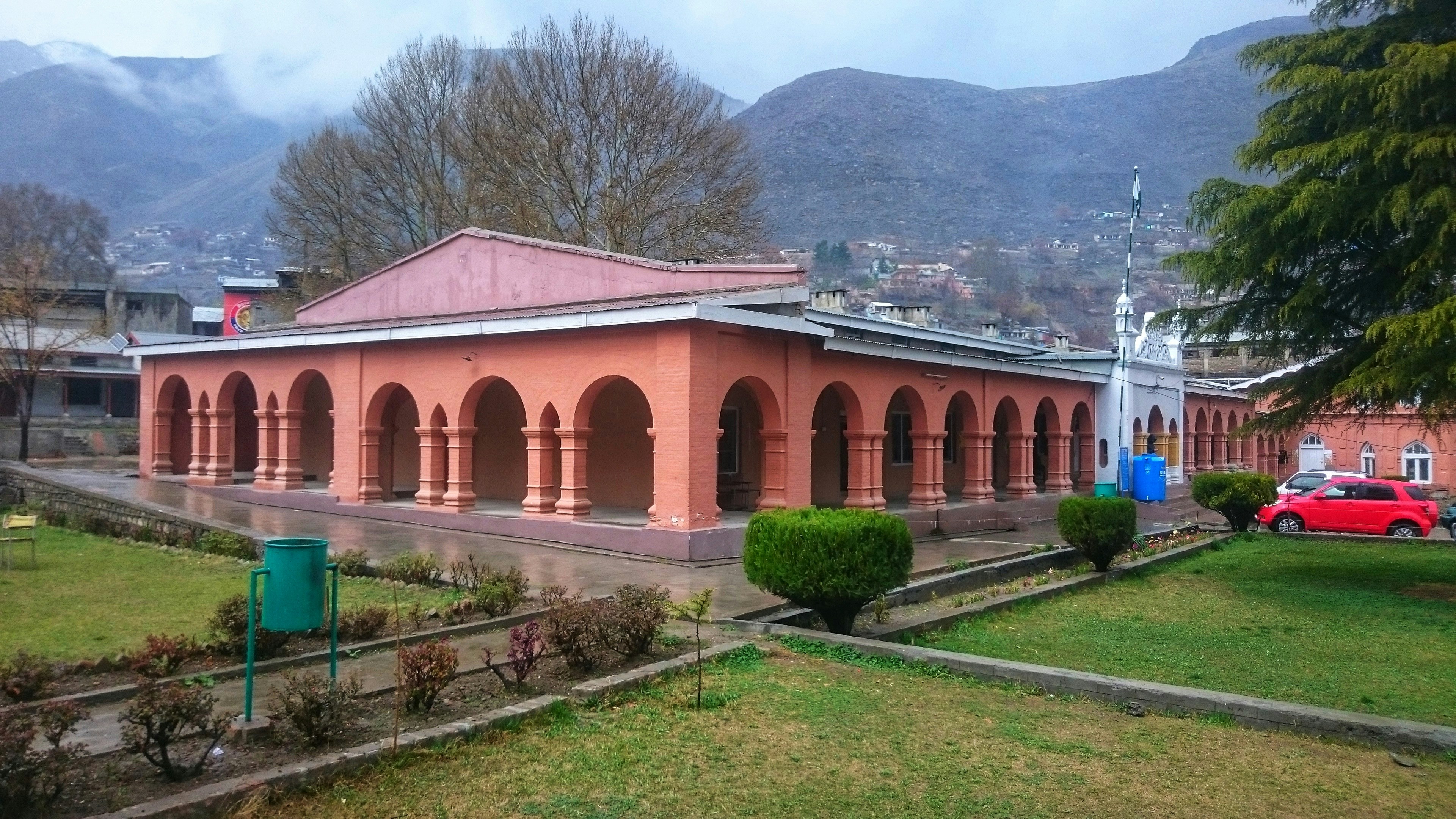 a red car parked in front of a pink building