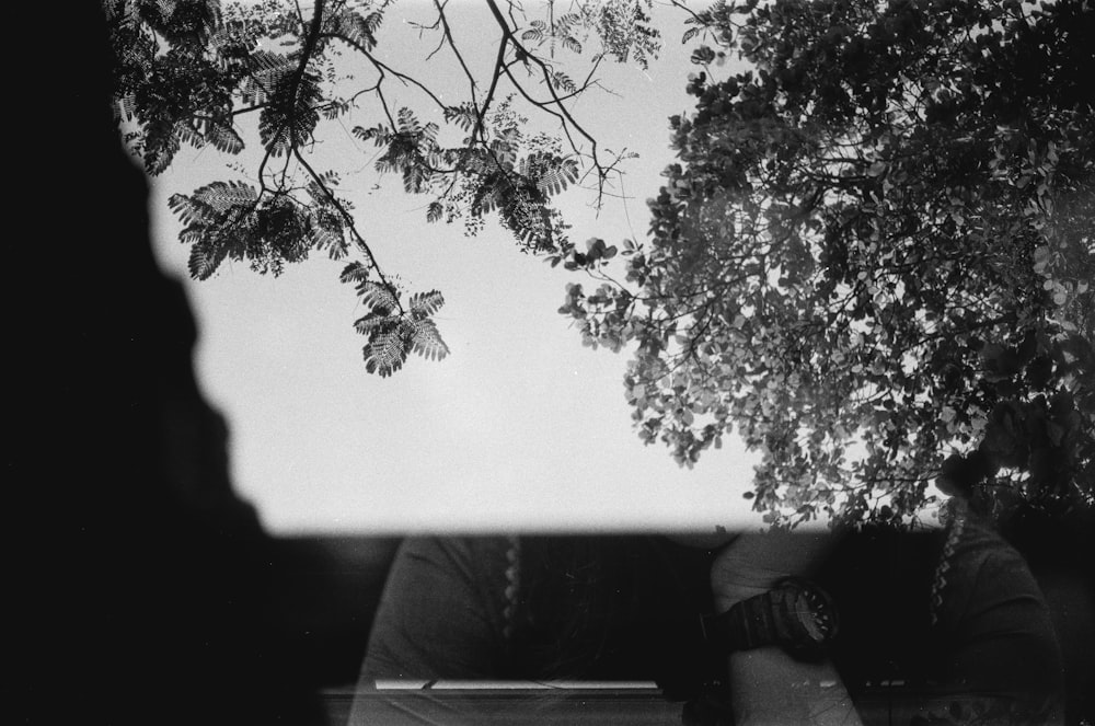 uma foto em preto e branco de uma pessoa sentada em um banco