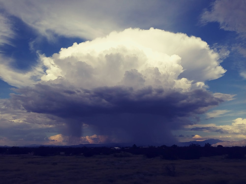 a large cloud is in the sky above a field