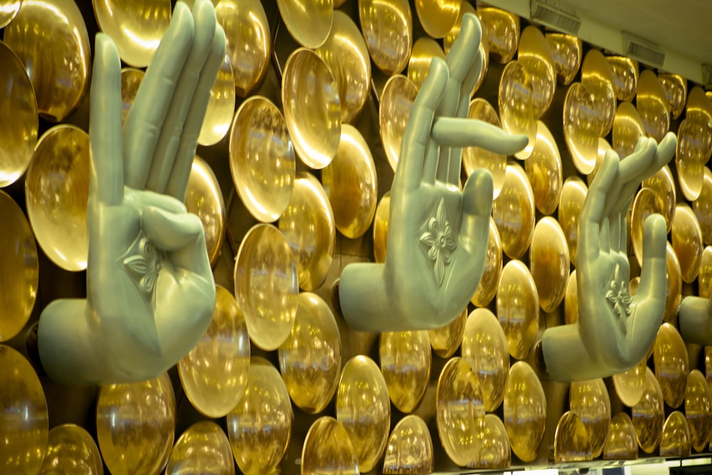 a wall of gold plates with hands and fingers on them