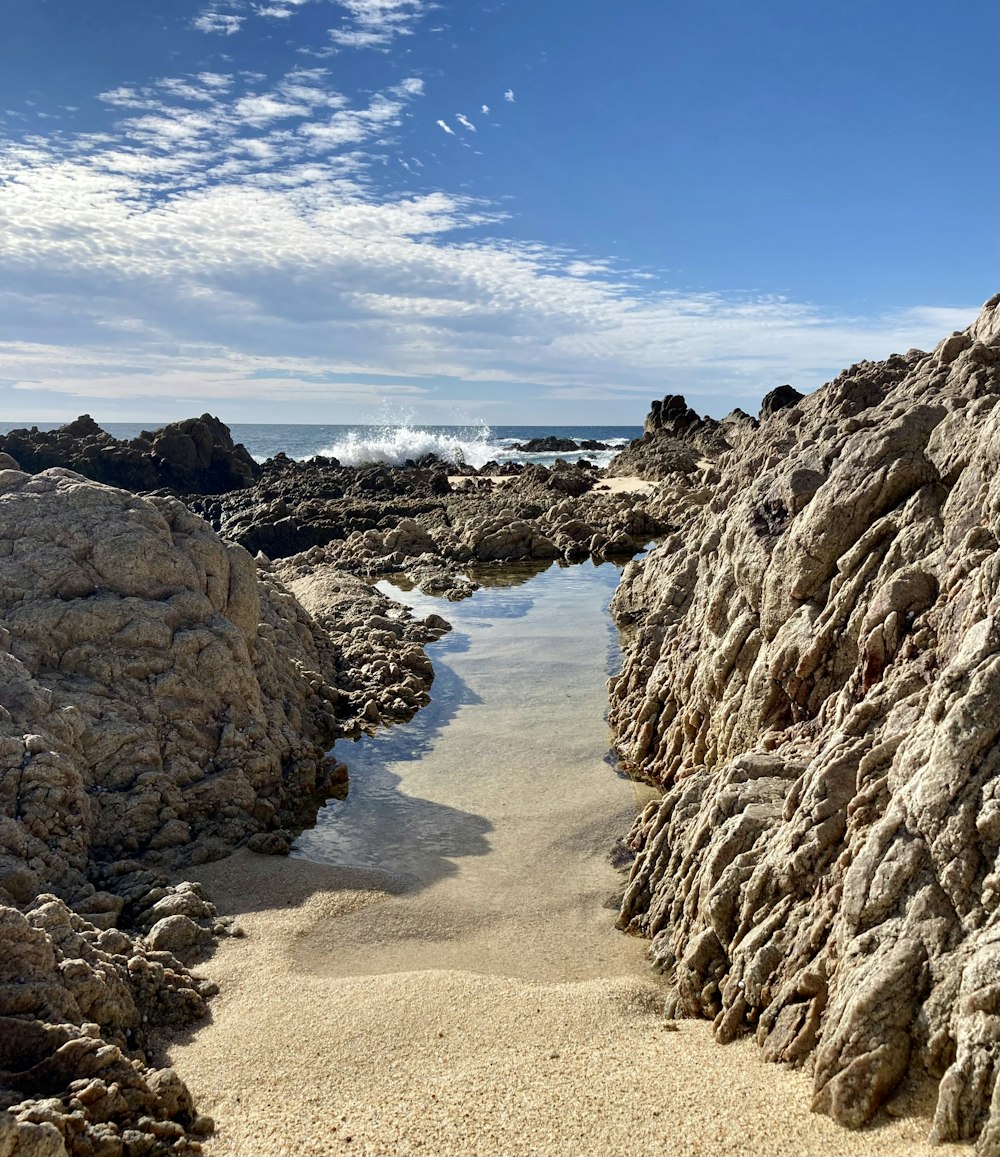 a sandy beach with rocks and a body of water