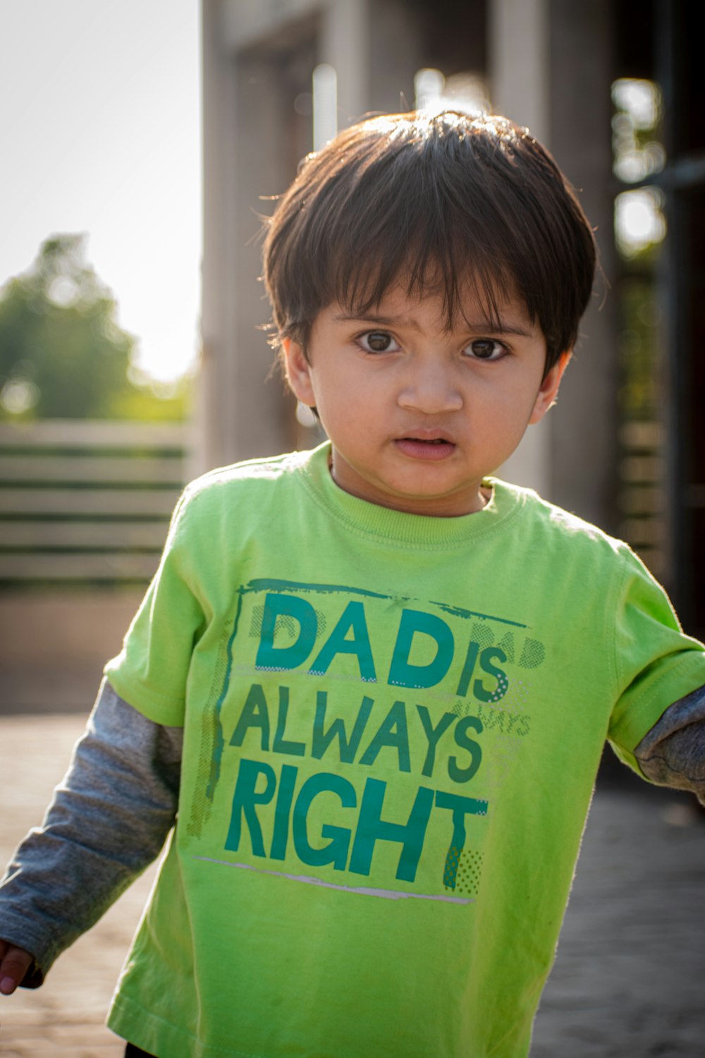 a young boy in a green shirt holding a frisbee