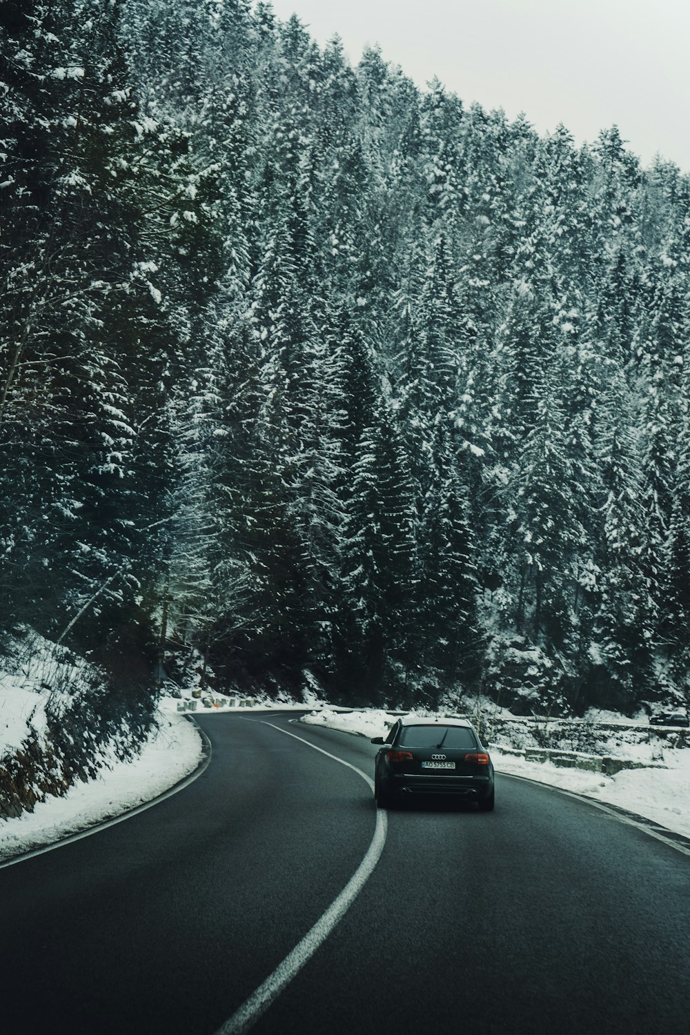 Ein Auto fährt eine verschneite Straße hinunter