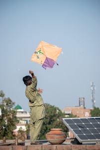 a man flying a kite on top of a roof