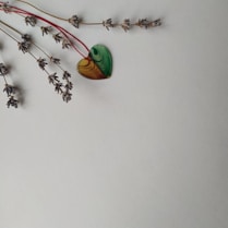 A pair of handmade polymer clay jewelry pieces resting beside a sprig of fresh lavender.