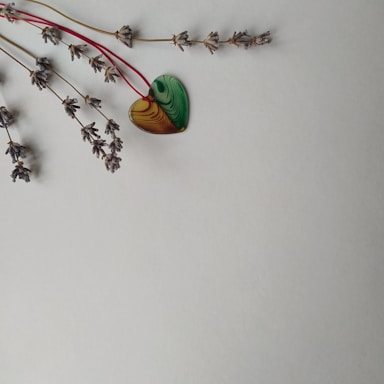 A pair of handmade polymer clay jewelry pieces resting beside a sprig of fresh lavender.