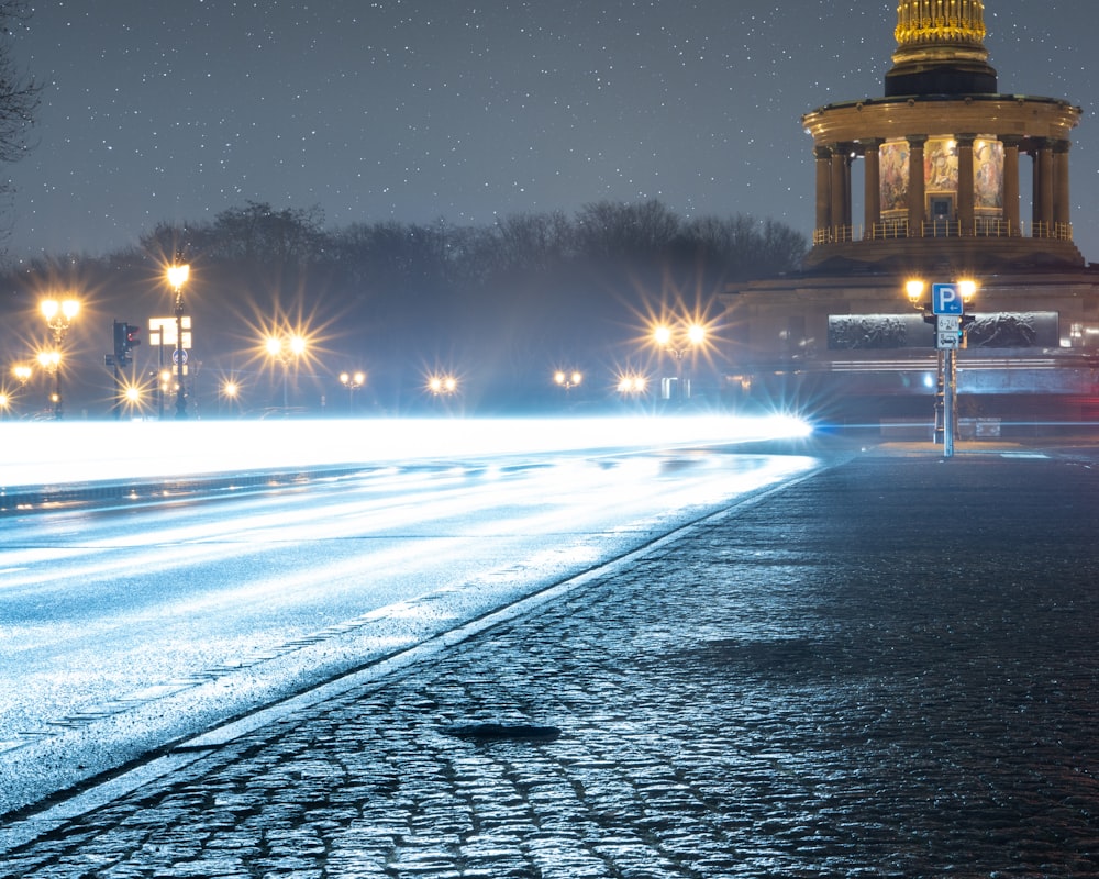 Una strada della città di notte con una torre dell'orologio sullo sfondo  foto – Berlino Immagine gratuita su Unsplash