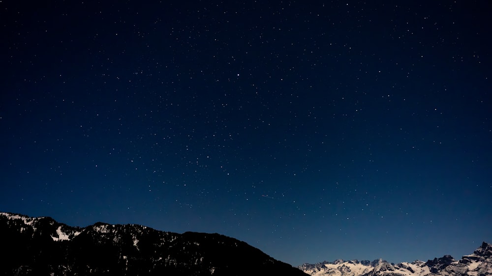 o céu noturno com estrelas acima de uma cordilheira