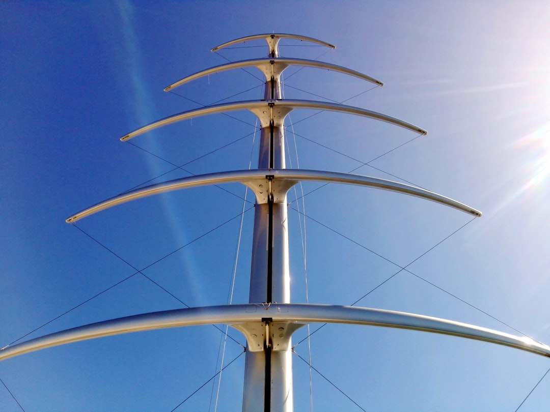 a tall metal structure with a sky background, Mast and spars of a modern saling yacht<p></figure>Mástil y vergas de un yate a vela moderno