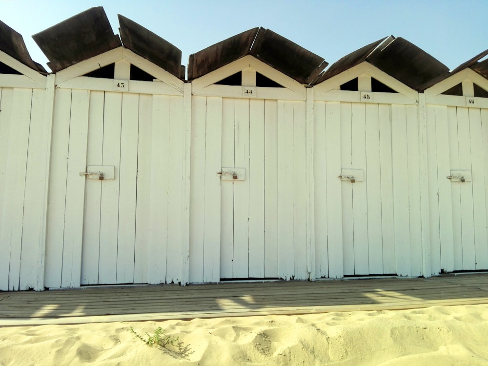 a row of white beach huts sitting on top of a sandy beach